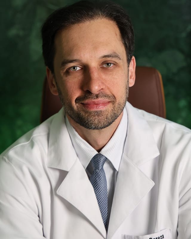 Dr. Bruno Bereza de jaleco no consultório